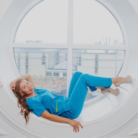 Девушка в медицинской одежде лежит на поддоконнике
